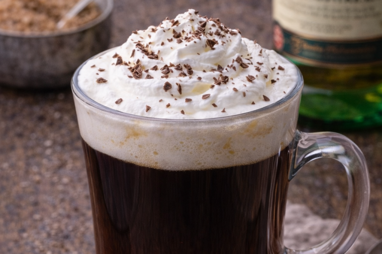 Kopp med svart kaffe, grädde och chokladspån på toppen.