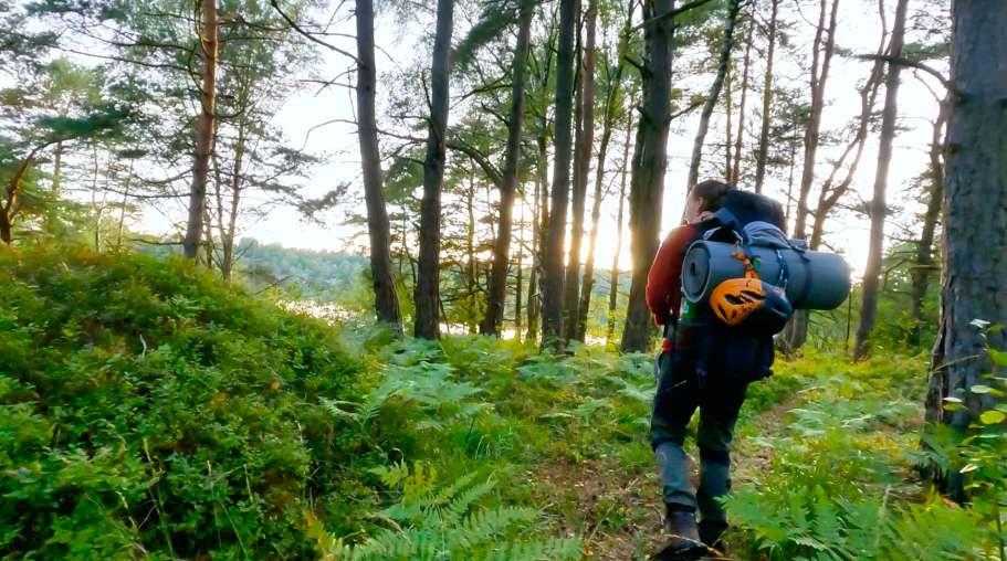 Rosita i solnedgången Vandrare med ryggsäck på stig i skog med solnedgång i bakgrunden.