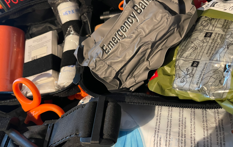 Första hjälpen-kit med bandage, nödutrustning, tourniquet, sax och traumagauze i en väska.