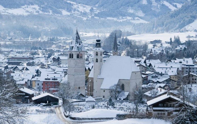 Berglandskap med snötäckta toppar och en kabinbana som svävar över dalen.