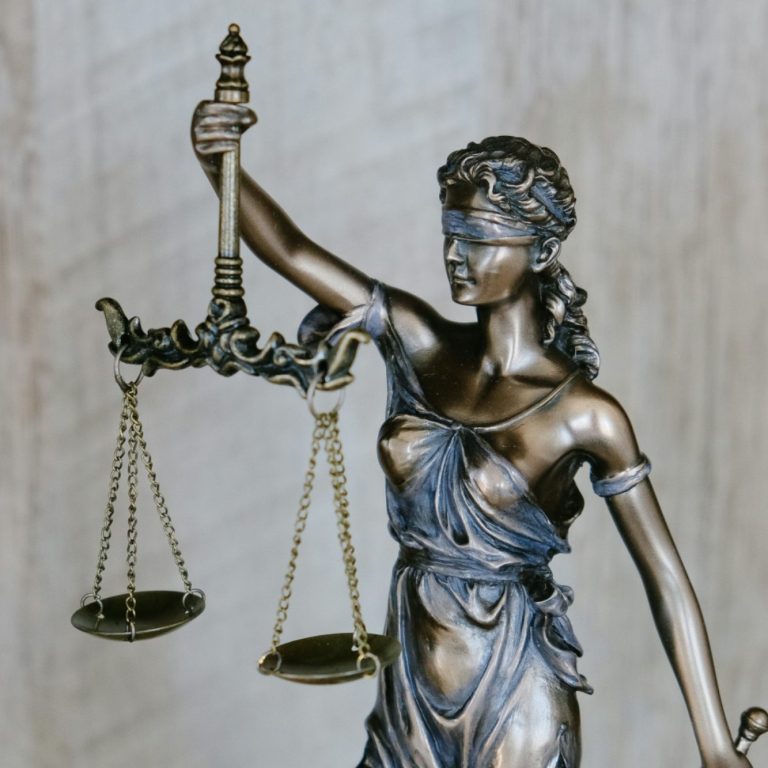 Staty av rättvisan, med ögonbindel och våg i vardera handen.