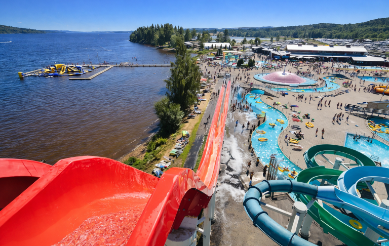 Utsikt över en vattenpark med rutschkanor och en sjö i bakgrunden.