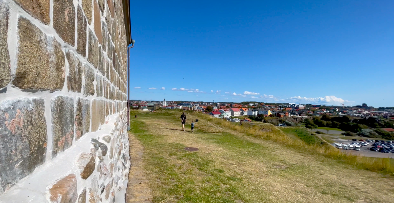 Varbergs Fästning Utsikt över ett landskap med gröna fält och hus under en klarblå himmel.