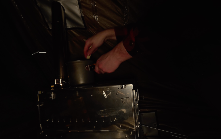 Händer som häller något i en liten metallbehållare i svagt ljus.