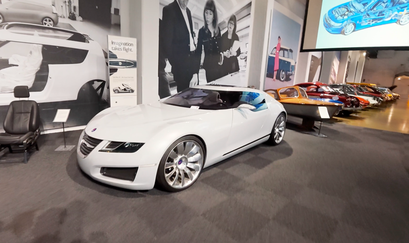 Saab Aero X Vit sportbil med futuristisk design, placerad i en utställning med andra bilar.