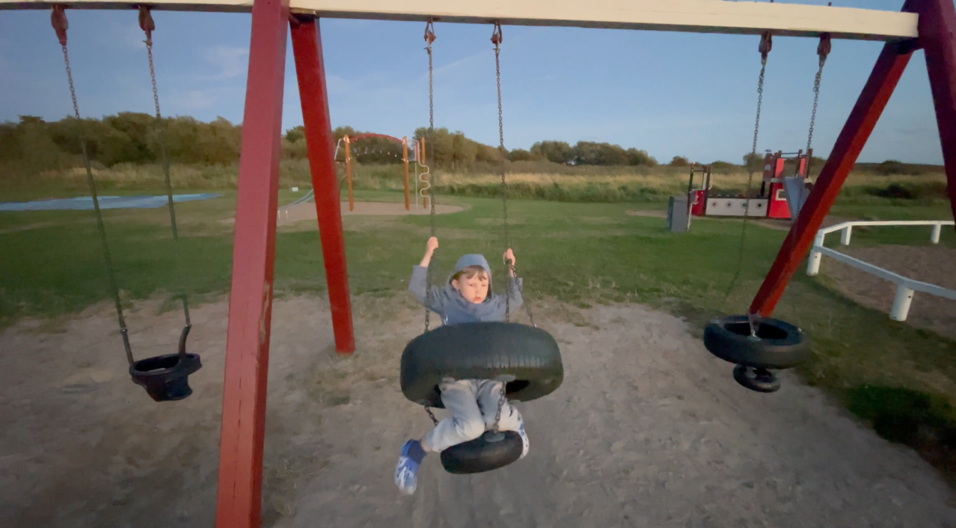 Leo Gungar Ett barn som svänger glädjefullt på en gungställning i en park.