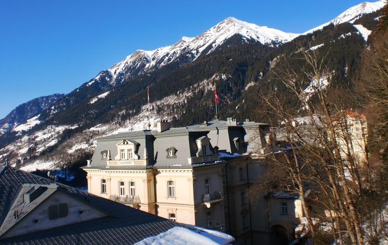 Vacker fjällutsikt med snötäckta toppar och en elegant byggnad i förgrunden.