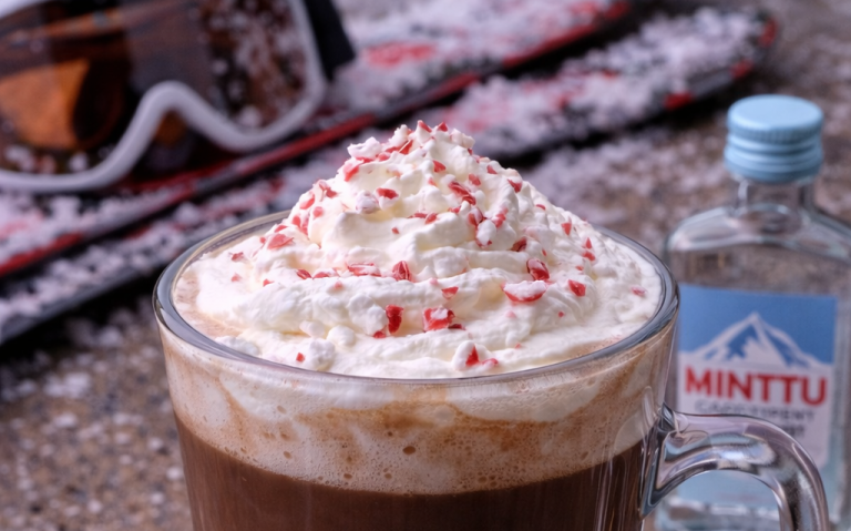 Kaffe med vispgrädde och strössel, snö och skidutrustning i bakgrunden.