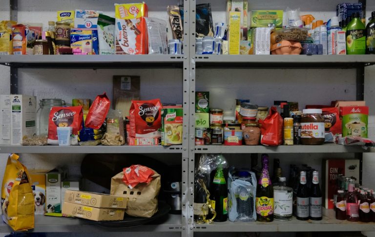 Hyllor fyllda med olika livsmedelsprodukter och drycker i förpackningar.