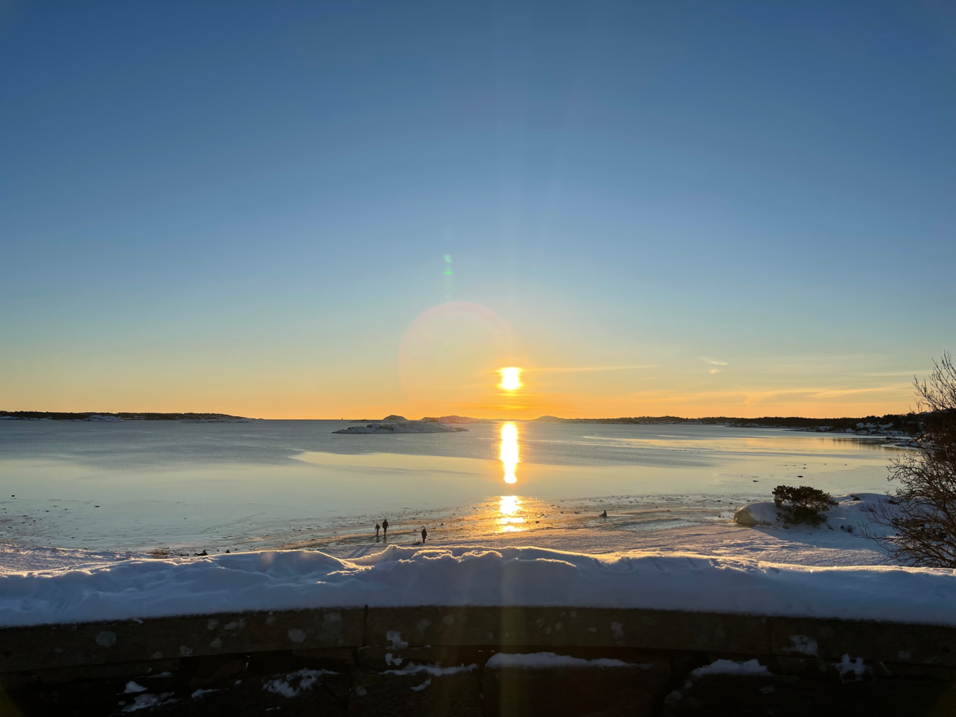 Solnedgång Solnedgång över en frusen sjö med snöiga kanter och klara himmeltoner.