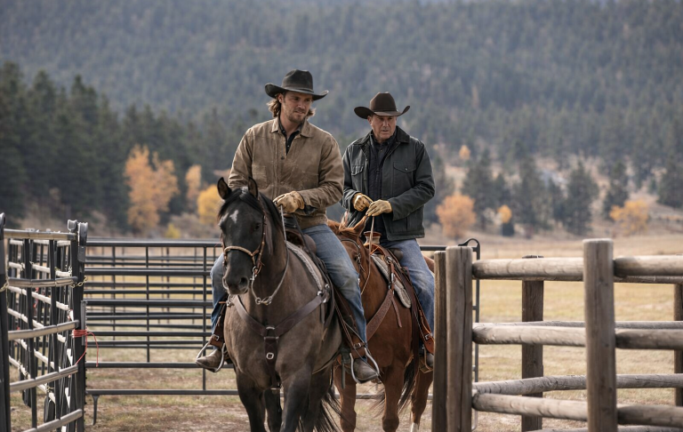 Två cowboys på hästar, klädda i cowboyhattar, rider genom en ranch.