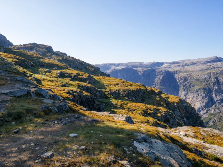 Bergig landskap med grön gräs och klippiga områden, omgiven av djupa dalar.