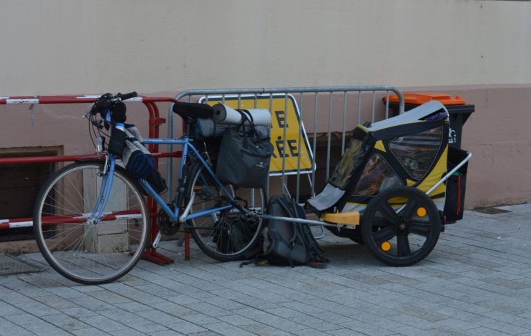 En cykel med packning och ett cykelanhängare står parkerad vid ett avspärrningsområde.