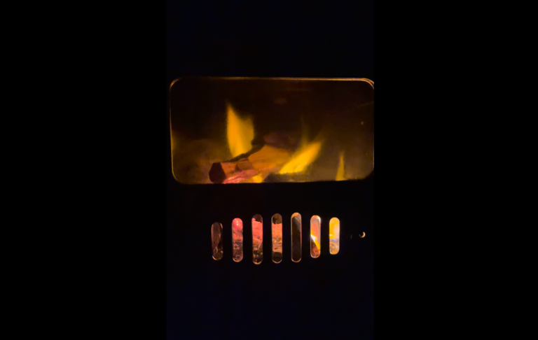 Eld som flammar i en vedspis med glödande ved underifrån.