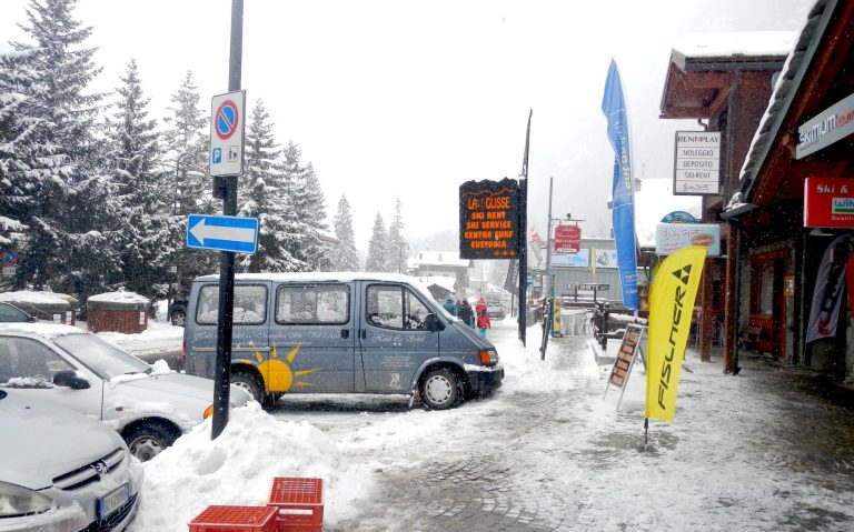 Snöigt gatulandskap med bilar, butiker och en temperaturvisare på -3 grader.