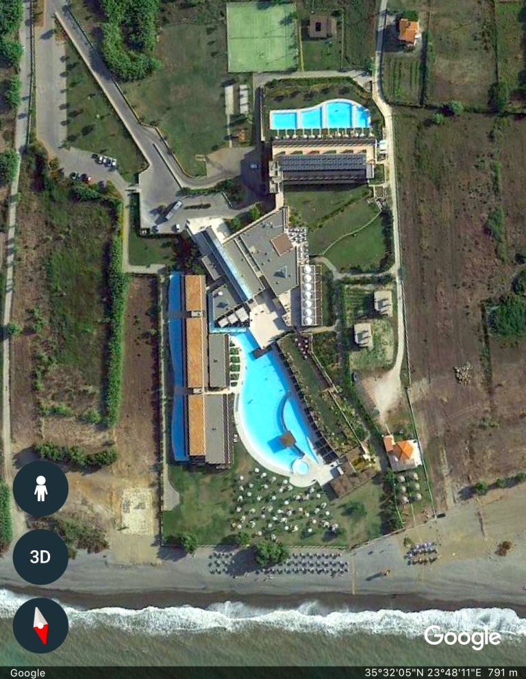 Vy över en resort vid kusten med flera pooler och omgivande grönområden.