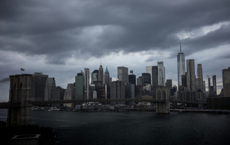 Mörka moln över New York Citys skyline med Brooklyn Bridge i förgrunden.