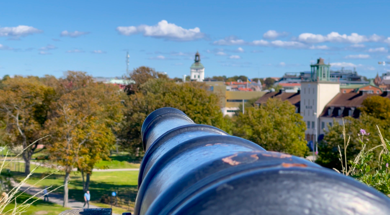 Kanon på Varbergs Fästning Utsikt över staden från en kanon med grönska och byggnader i bakgrunden.
