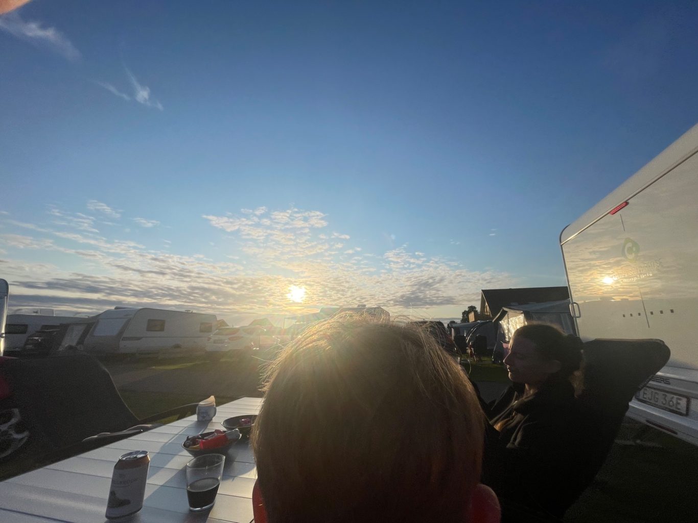 Middag i Solnedgången Solnedgång över ett landskap med människor som sitter vid ett bord.