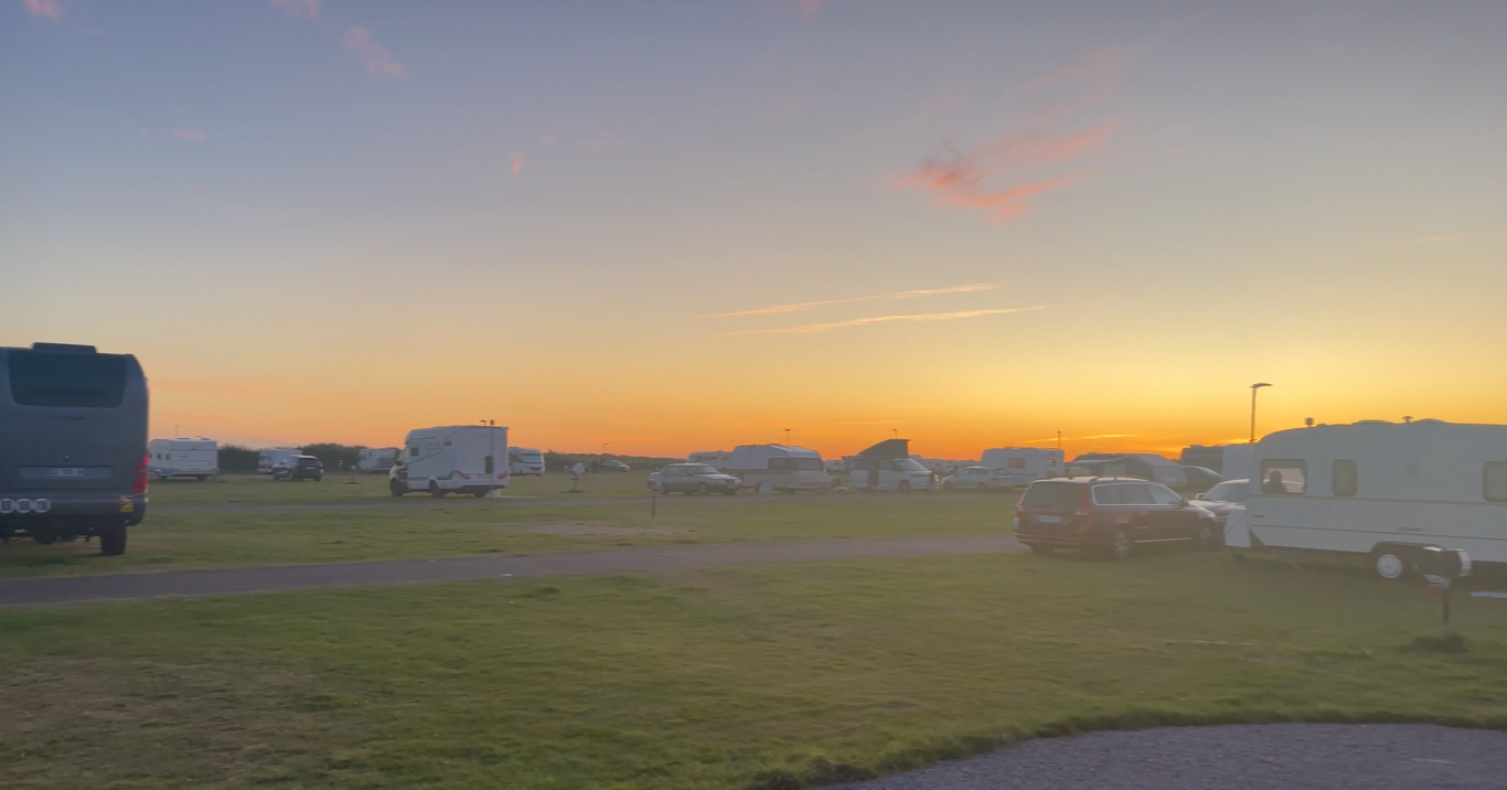 Solnedgång över Campingen i Björkäng Campingområde vid solnedgång med husvagnar och grön gräsyta.