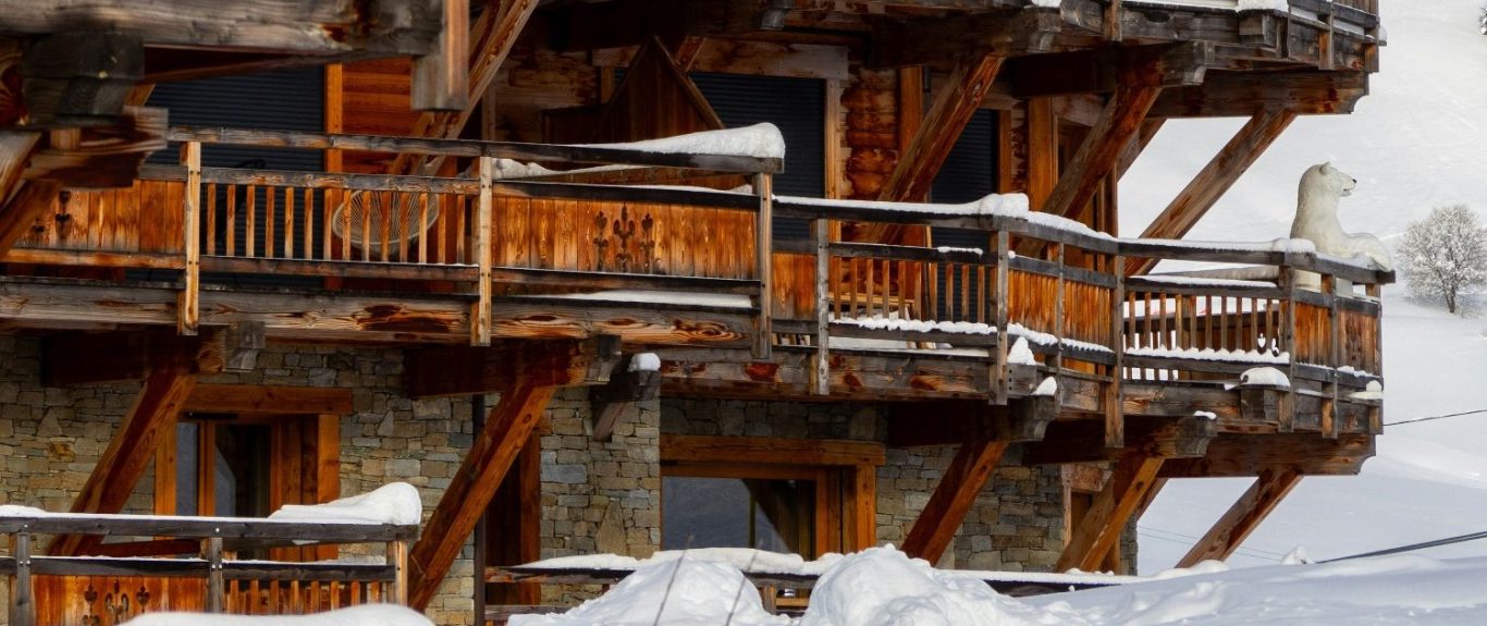 Klassisk fjällstuga med träbyggnader, balkonger och snötäckta omgivningar.