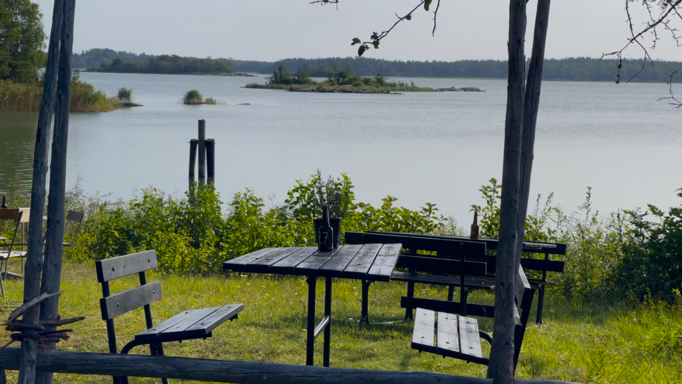 Algots på Udden Utsikt över sjön med en bänk och ett bord i förgrunden. Grönska runt om.