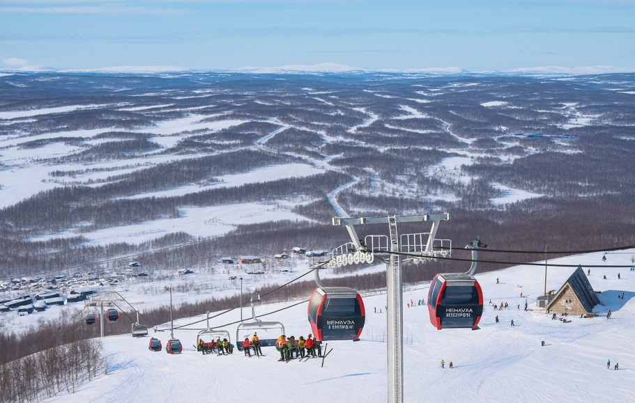 Illustration av Skidliftar över snötäckta fjäll och träd i fjärran. Klarblå himmel.