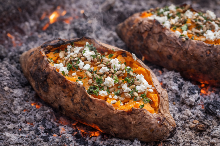 Bakad sötpotatis med ost och örter, placerad i glödande aska.