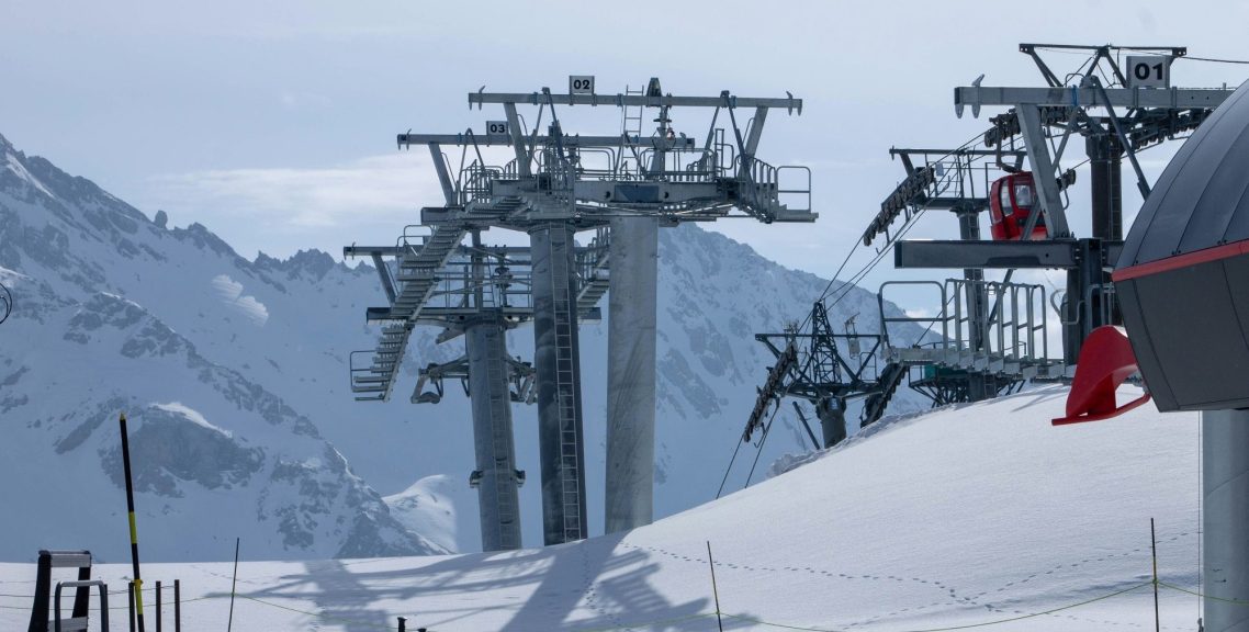 Skidliftar i snötäckta fjäll med berg i bakgrunden.
