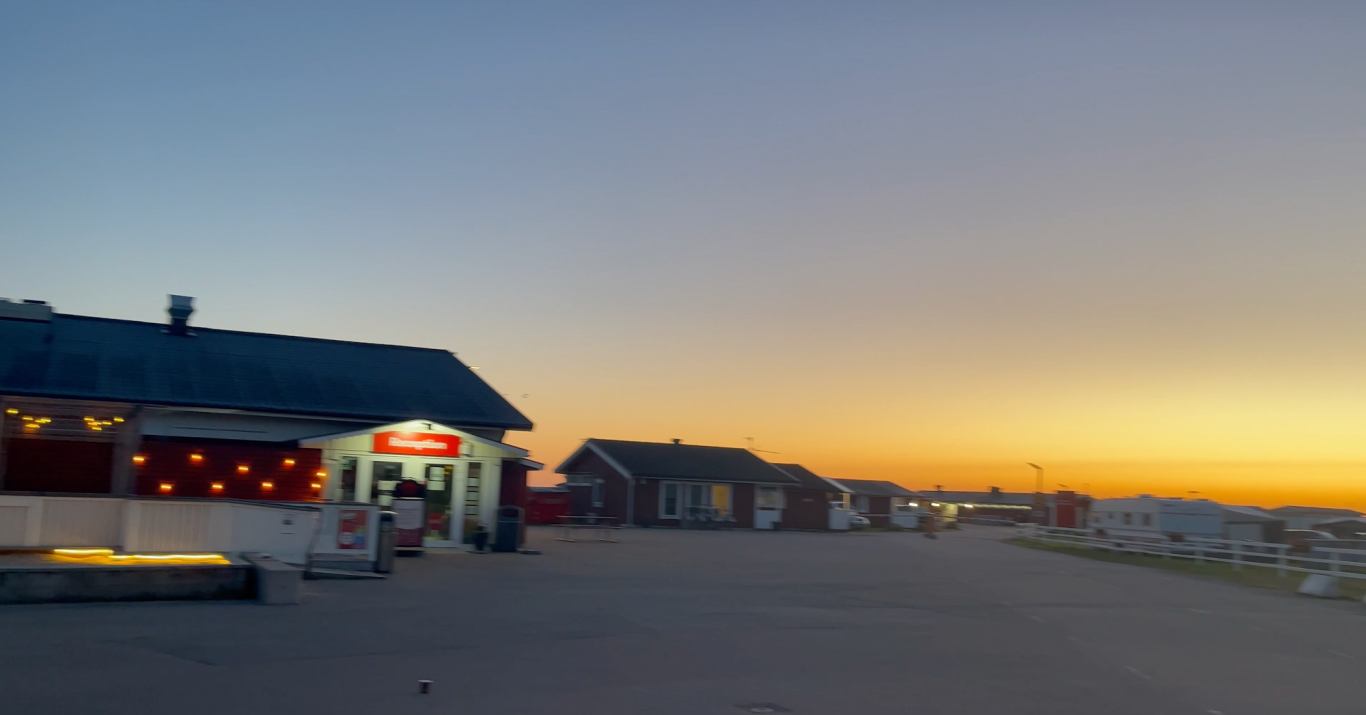 Solnedgång över Campingen i Björkäng Vacker solnedgång över en gata med hus och ljusskyltar.