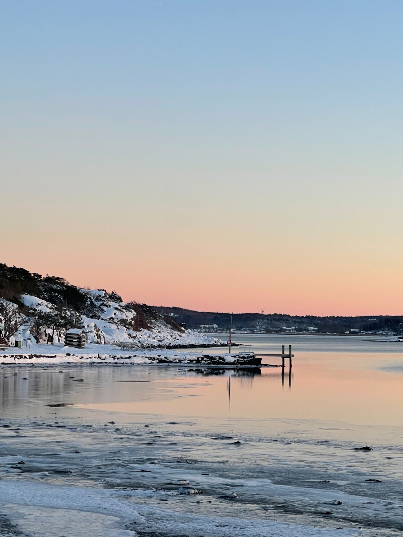 Solnedgång över Kungsbackafjorden Vinterlandskap vid vattnet med snö, is och en ljusrosa himmel.