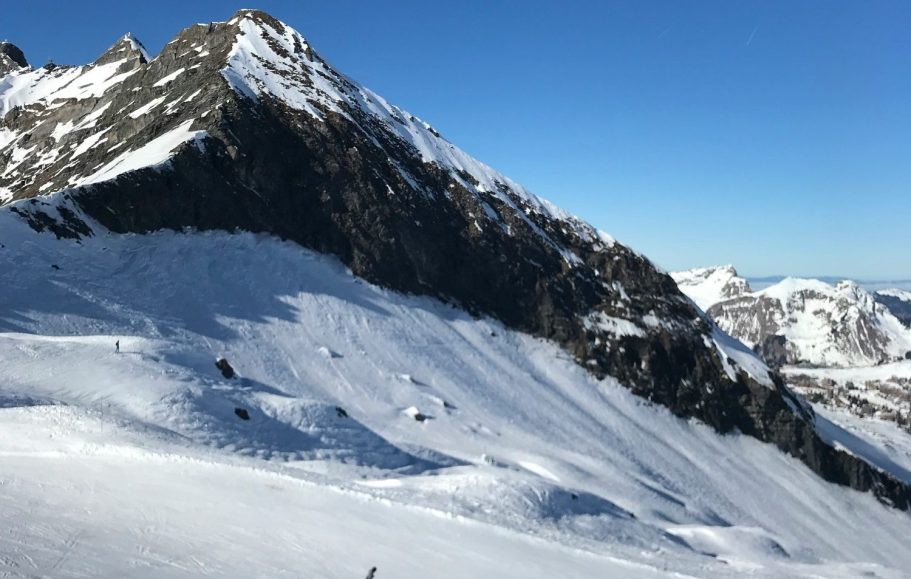 Snötäckta alpberg och dalar under en klarblå himmel.