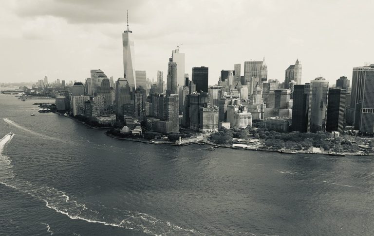 Svartvitt panorama av New Yorks skyline med floden i förgrunden.