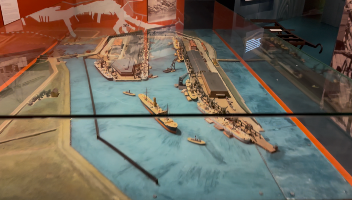 Göteborgs hamns historia Modell av en hamn med fartyg och kajer, på en blå yta.