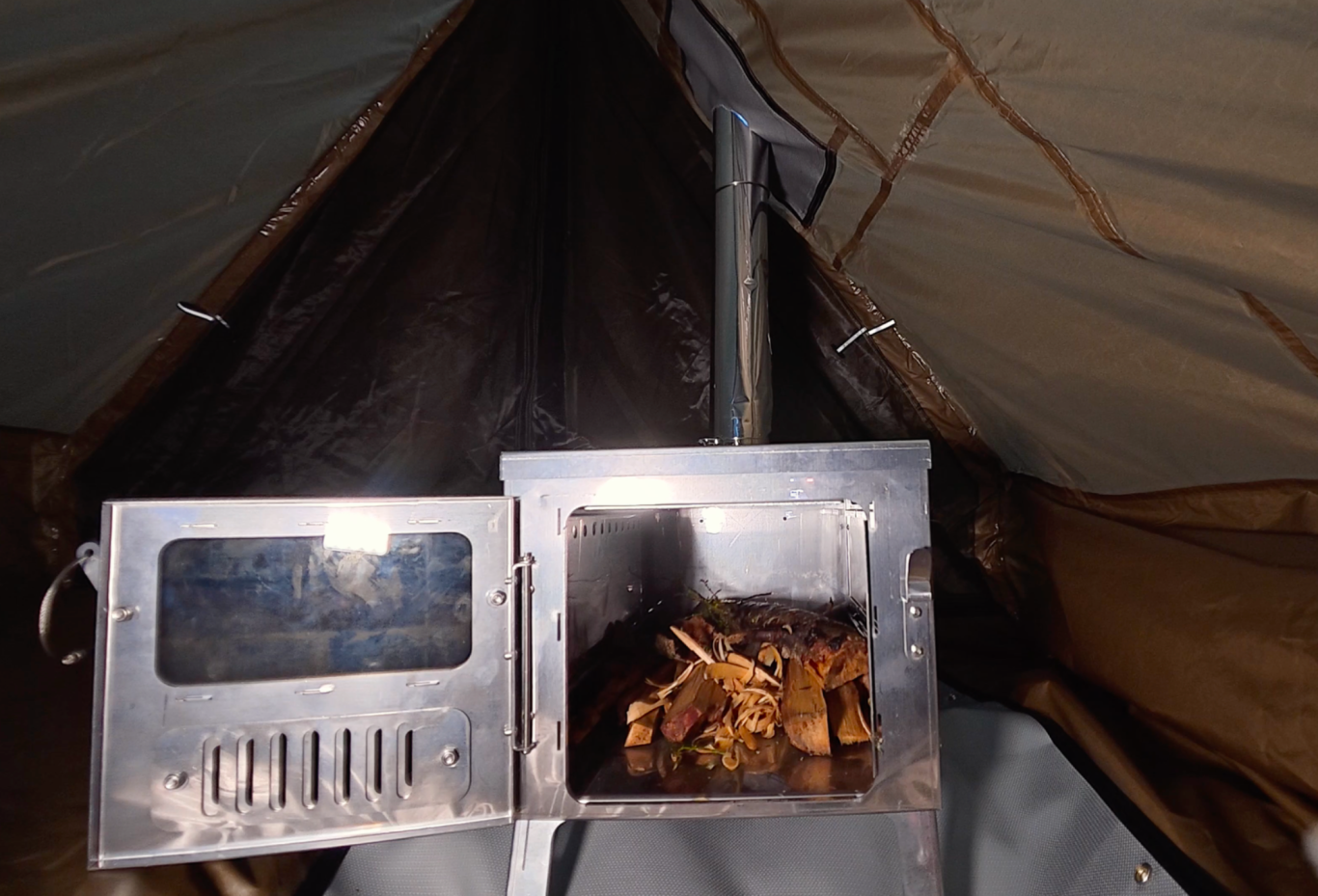 Kaminen En spis inuti ett tält, med rökutsläpp och eld inuti.