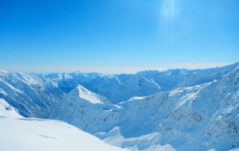 Snöklädda berg och dalar under klarblå himmel.