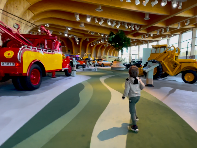 Barn går på en kurvig väg i en utställning med mottagna fordon.