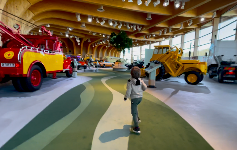 Barn går genom en utställning med traktorer och maskiner i en ljus lokal.