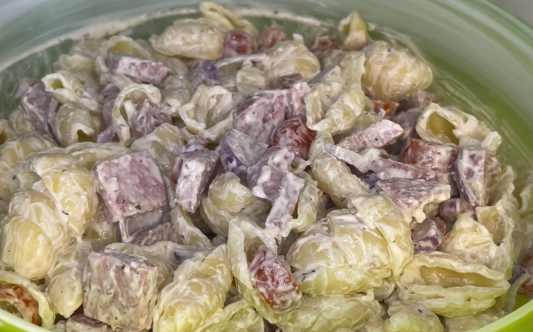 Krämig pastarätt med skinka och soltorkade tomater i en grön skål.