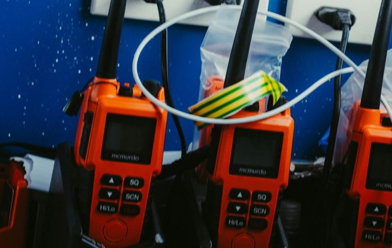 Orange handhållna radioapparater på en arbetsbänk med sladdar och en plastpåse.