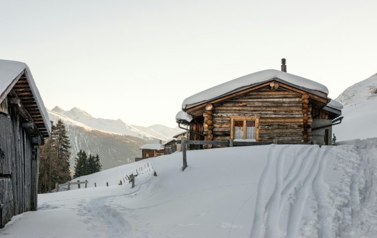 Fjällstuga omgiven av snötäckta landskap och berg.