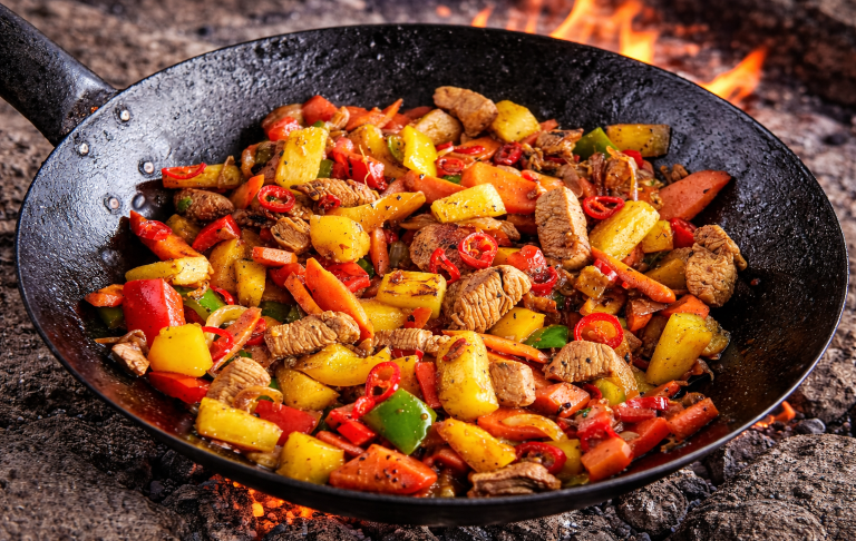 Wok med grönsaker och kött i en eldgul miljö. 