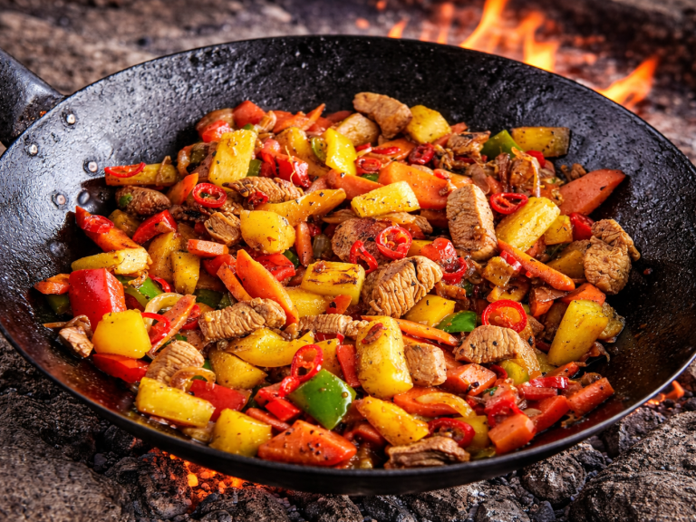 Grillad blandning av grönsaker och kött, med färgglada ingredienser och rökig bakgrund.