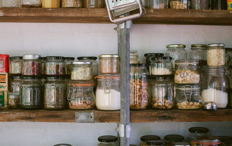 Hyllor med olika glasburkar som innehåller torrvaror och kryddor.
