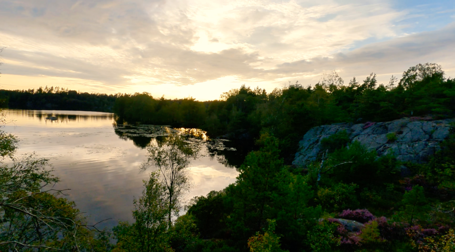 Solnedgång över sjön Lugn sjölandskap med spegelblanka vattenytor och en solnedgång i bakgrunden.