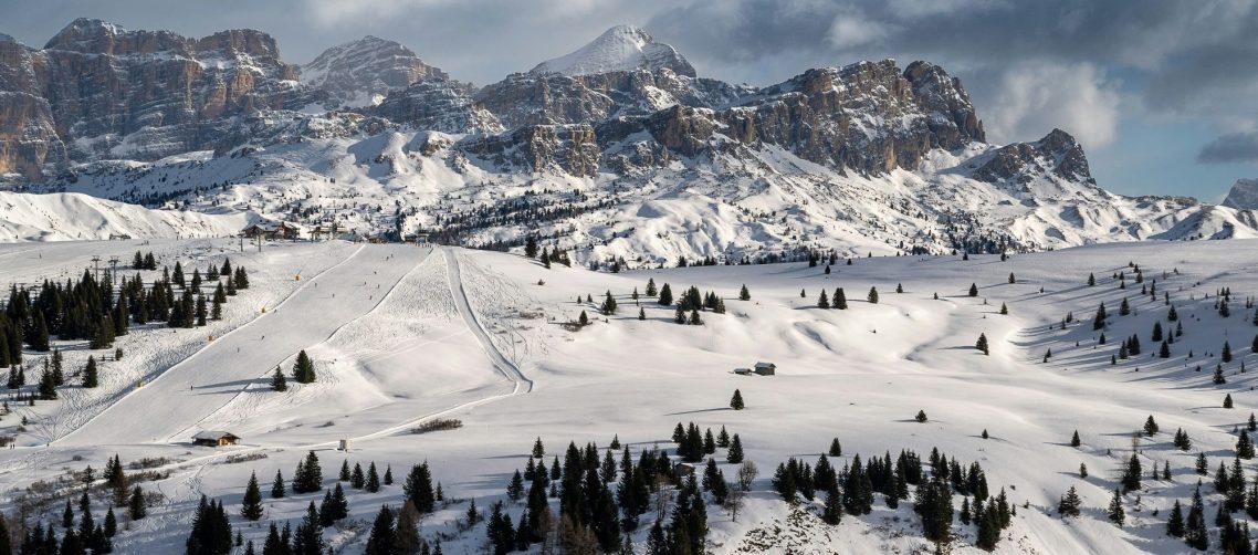 Vinterlandskap med snötäckta toppar och en dal fylld av träd.