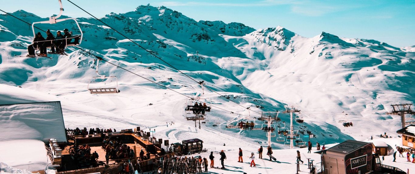 Skidorter med liftar och snötäckta alpberg i bakgrunden.