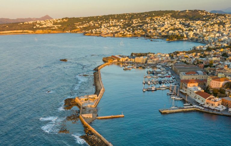 Utsikt över en hamn med småbåtar och kustlinje i solens glöd.