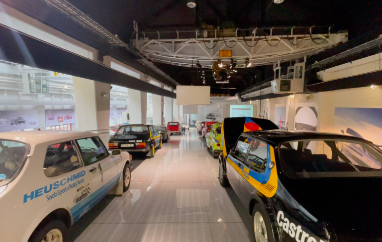 Rallybilarna på Saab Car Museum Utställning med flera vintage-bilar i en modern bilsalong.