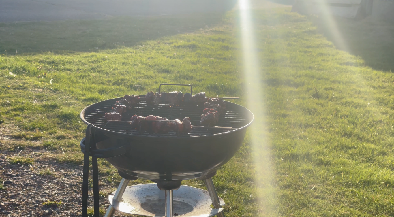 Grillar Grillspett Grill med korv som grillas på en grön gräsmatta i soligt väder.